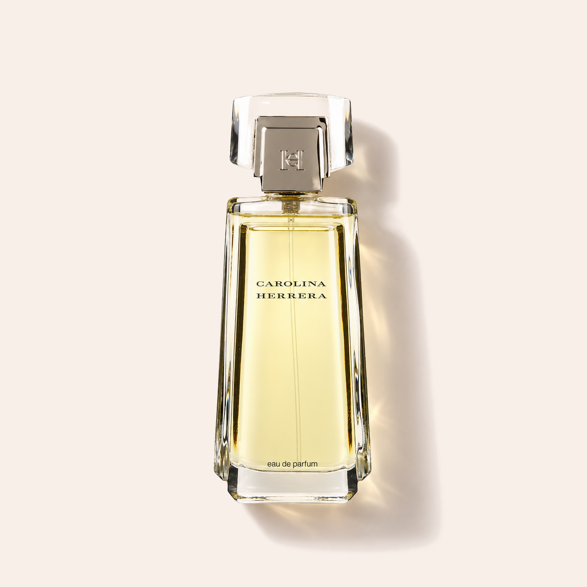 Carolina Herrera EDP 100 ml, flakon vleže na béžovém pozadí – MrRizz