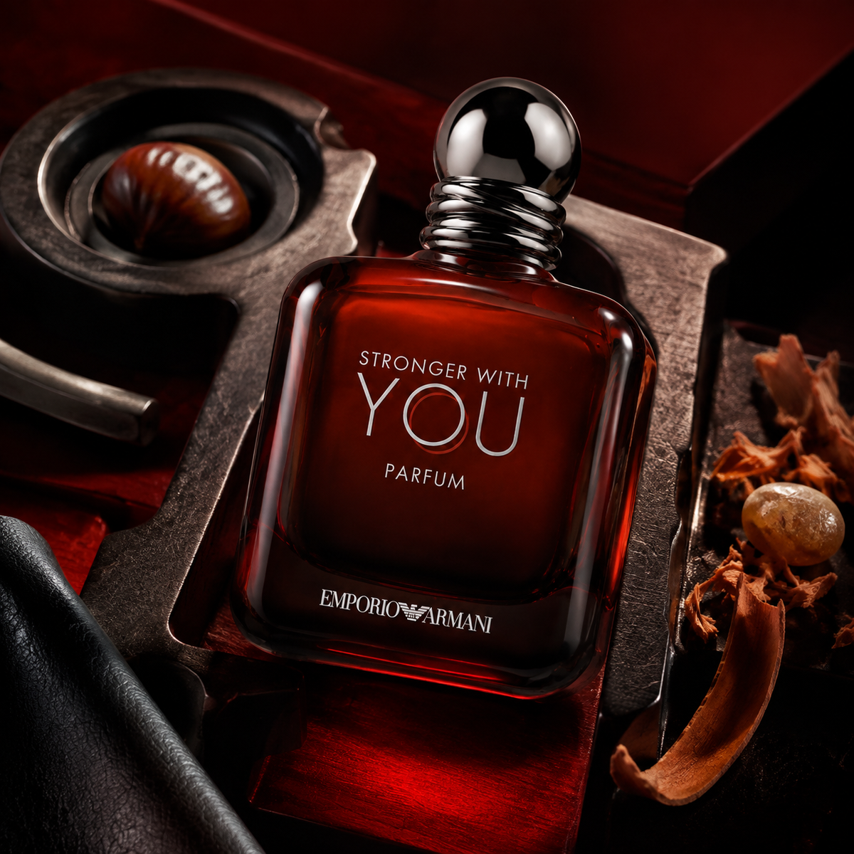 Emporio Armani Stronger With You Parfum položený v červeně osvětleném zátiší s kaštanem a dřevěnými hoblinami – MrRizz